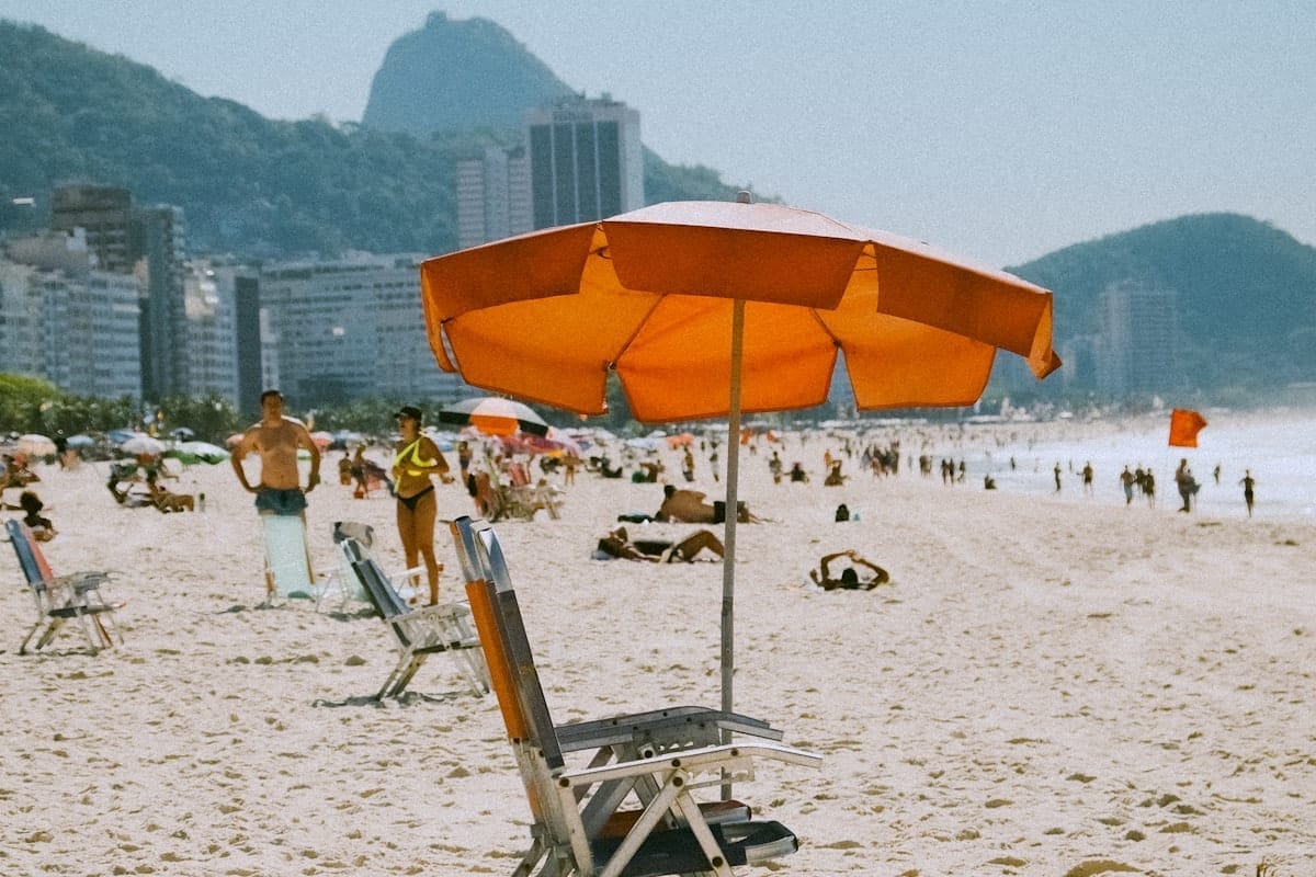 Cadeira e guarda-sol na praia com pessoas ao fundo